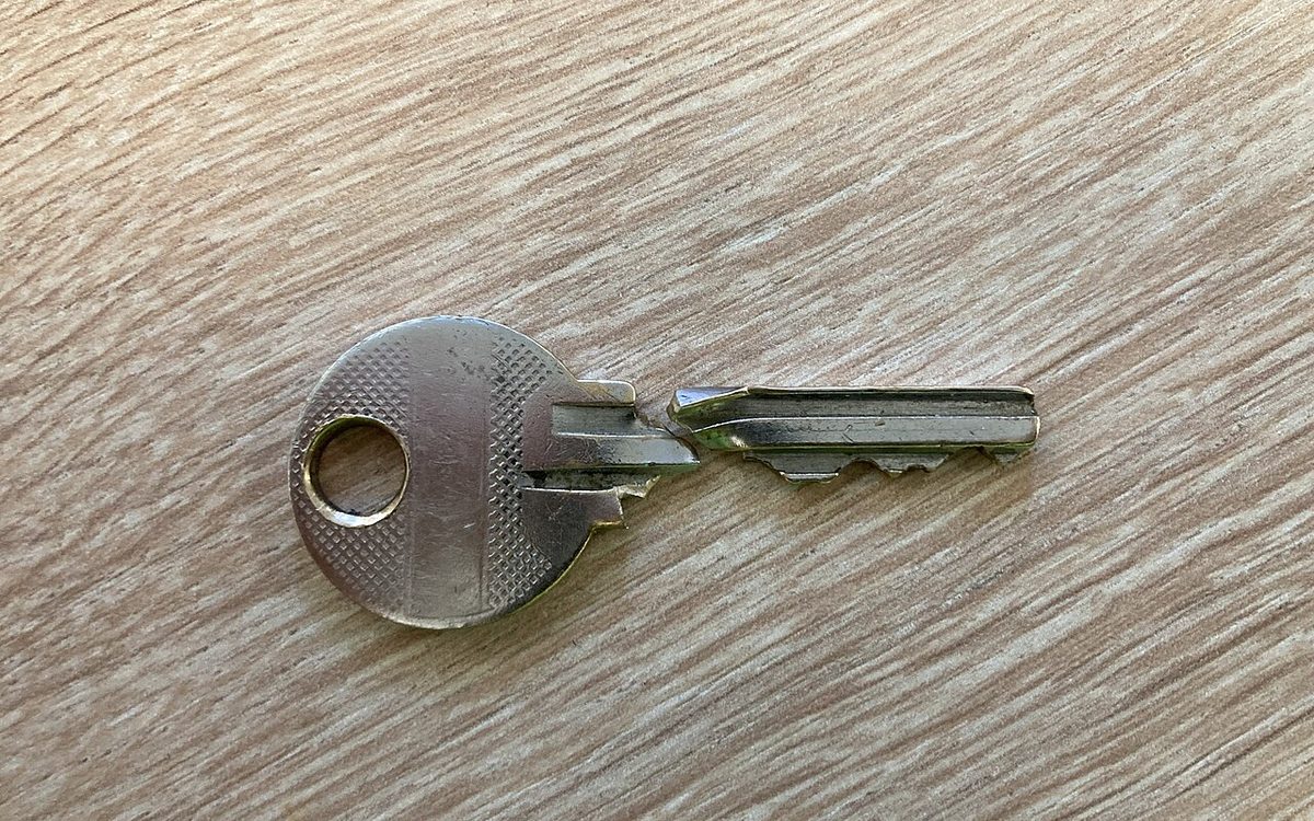 Clé de porte abîmée posée sur une table en bois